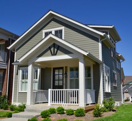 Gray two-story house with white trim and a covered front porch on a sunny day