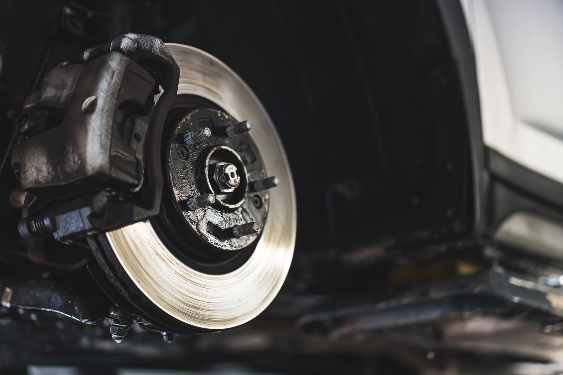 Close-up of a car’s front brake disc and caliper in a garage