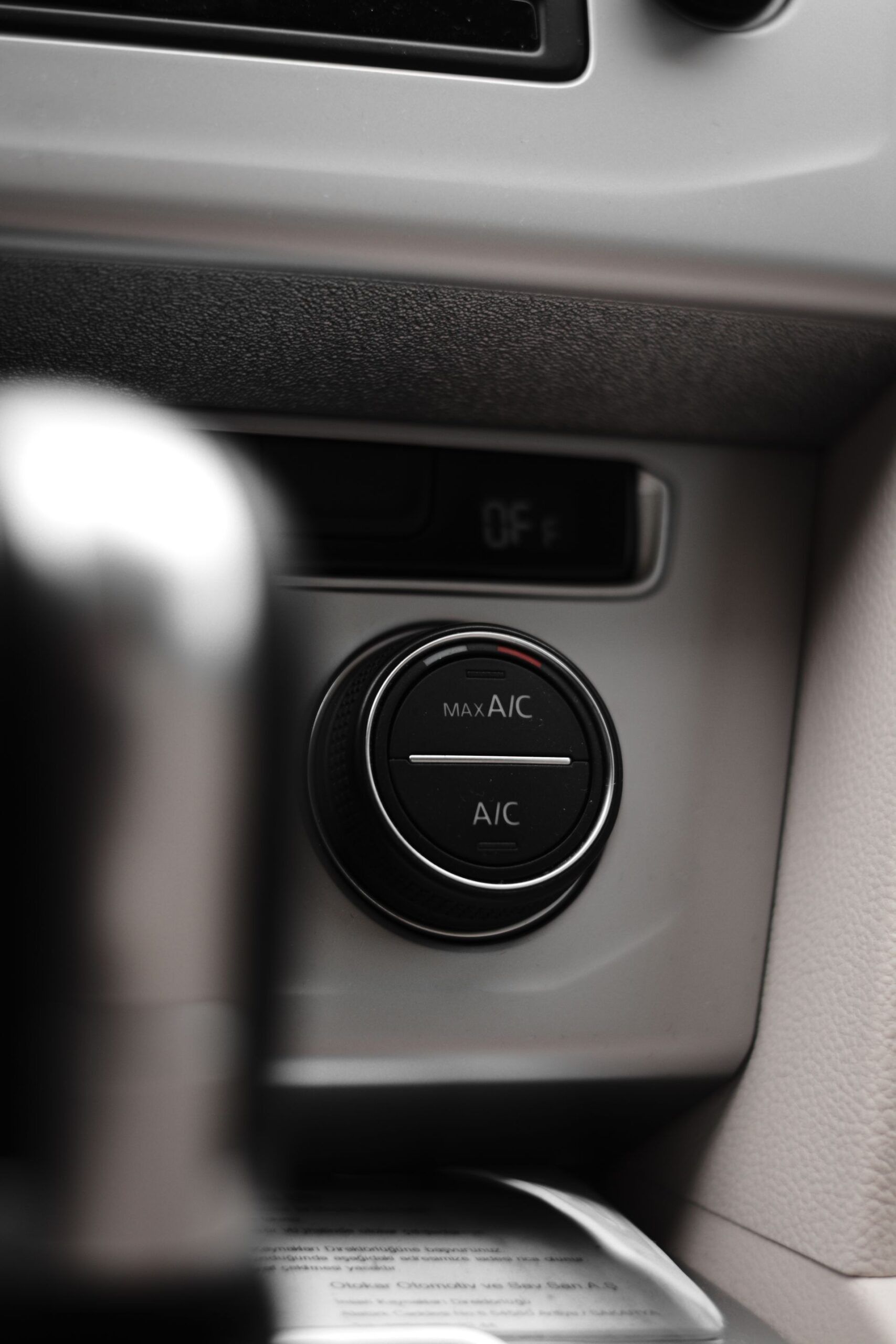 Car climate control dial with temperature and A/C buttons on a gray dashboard