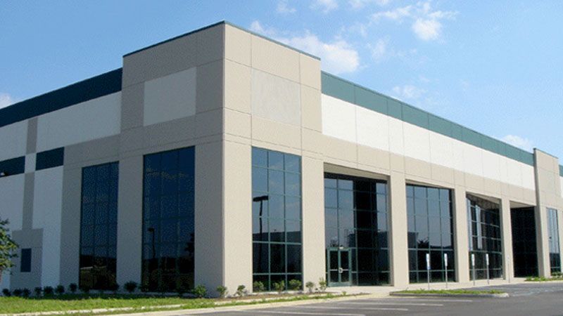 Empty industrial warehouse with high ceiling, yellow overhead crane, and open bays letting in daylight