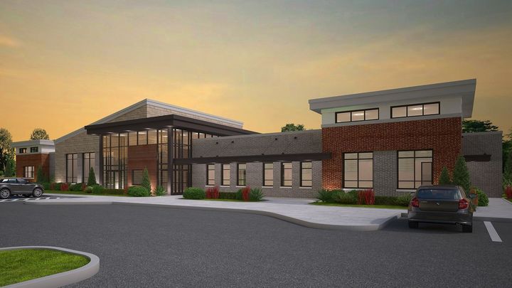 Modern brick building exterior at sunset with a curved driveway and parked car