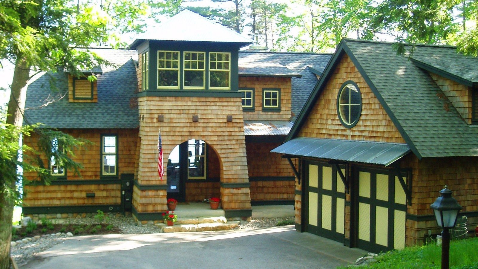 Stone archway entrance to a rustic timber building with dark roofs and surrounding trees