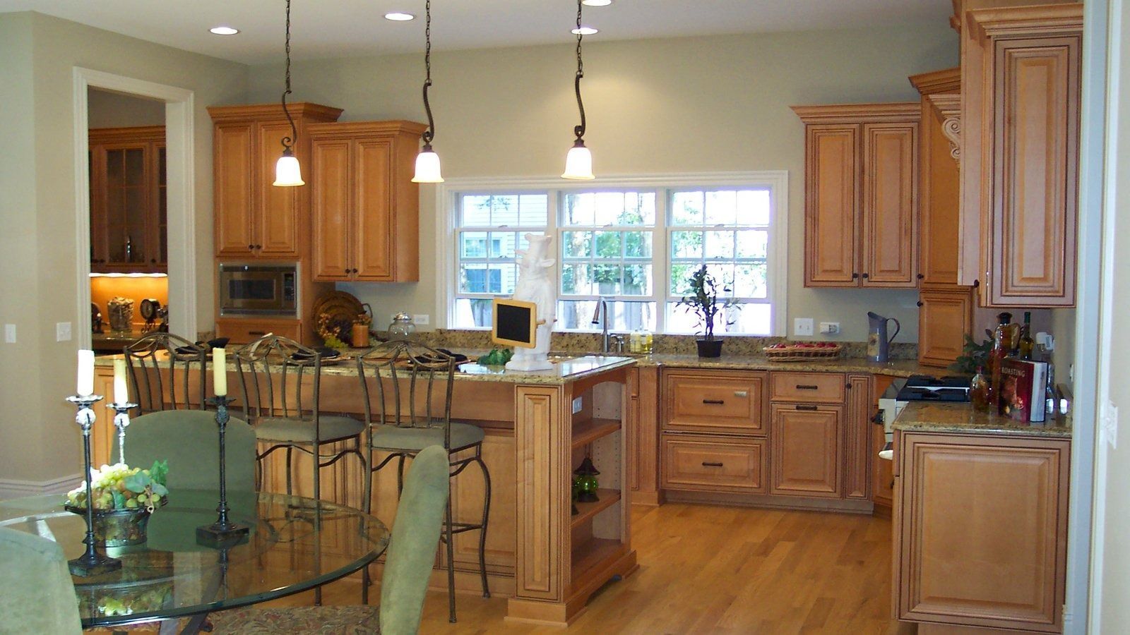 Bright modern kitchen with wood cabinets, island seating, and large window over hardwood floors