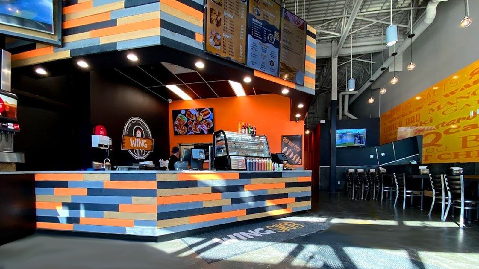 Modern café interior with orange and black décor, counter seating, and sunlight streaming through the windows