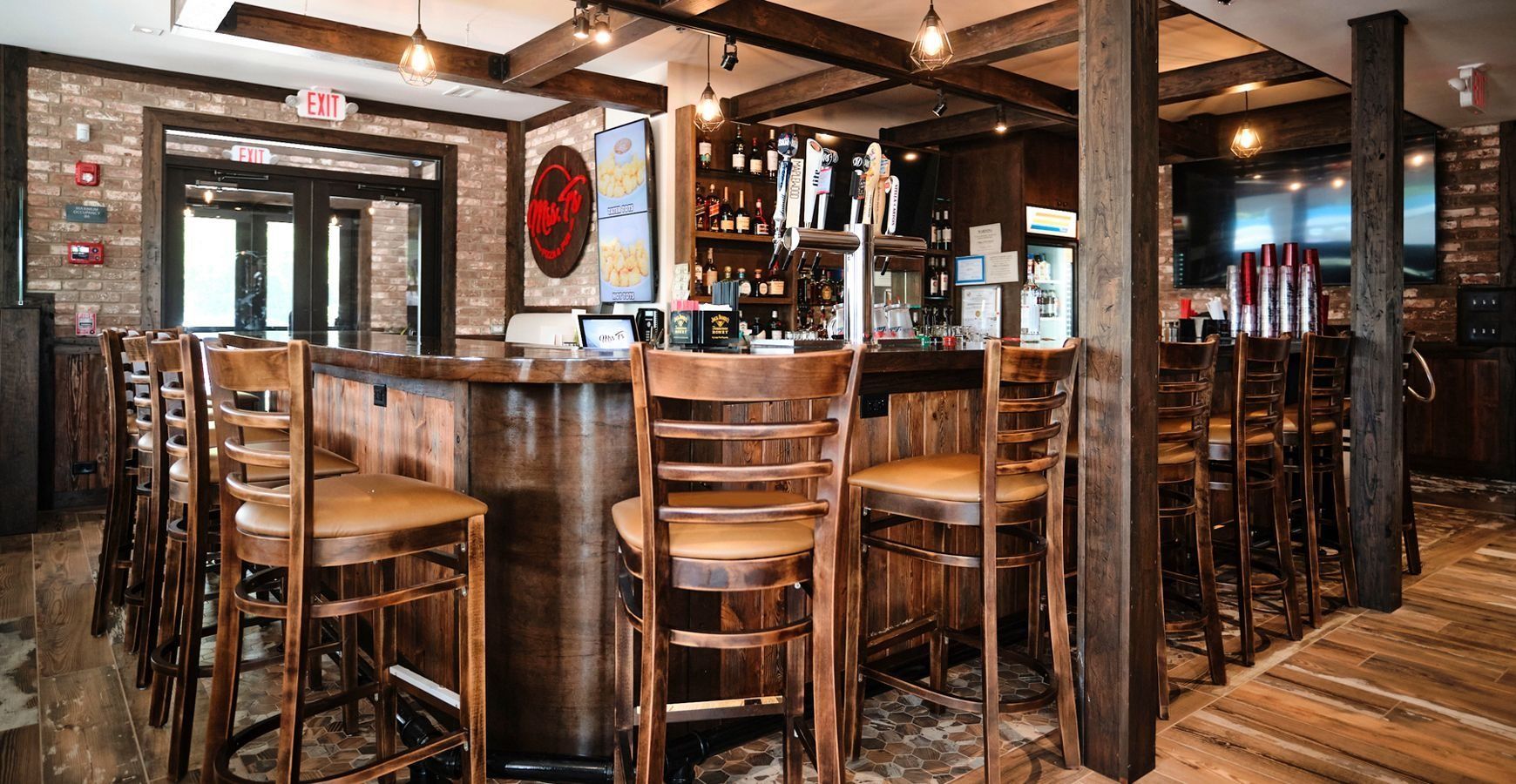 Rustic bar interior with wooden stools, exposed beams, and warm lighting