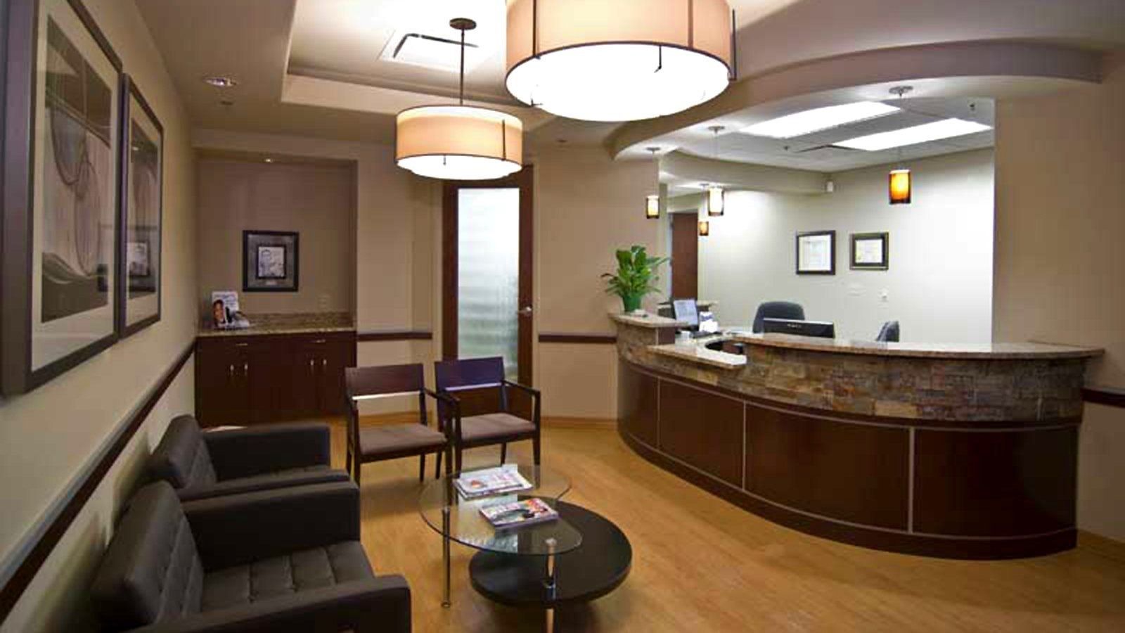 Modern office lobby with curved wood reception desk, seating area, and pendant lights.