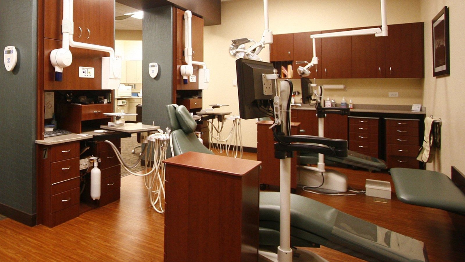 Dentist office with exam chair, cabinets, sink, and dental tools under bright lights