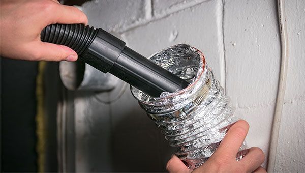 A person is using a vacuum cleaner to clean a duct.