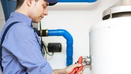 A man is fixing a water heater with a wrench.