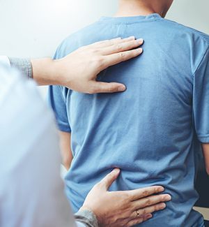 A man in a blue shirt is getting his back examined