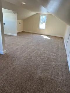 attic room with beige walls and repaired brown carpet