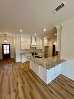 a kitchen with white cabinets , granite counter tops , and hardwood floors
