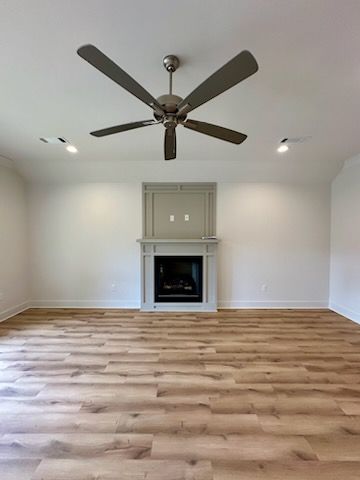 an empty living room with a fireplace and ceiling fan