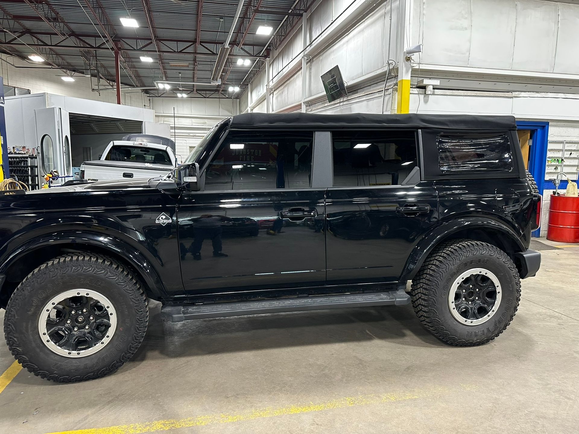 A black ford bronco is parked in a garage.