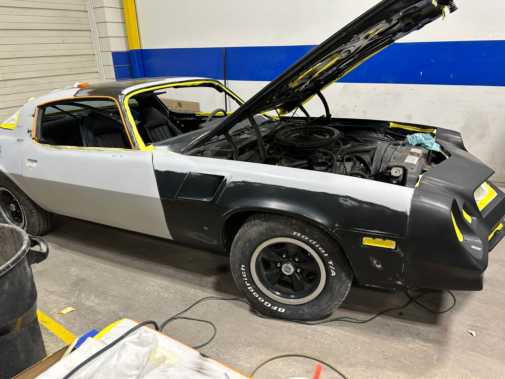 A car with the hood up is sitting in a garage.