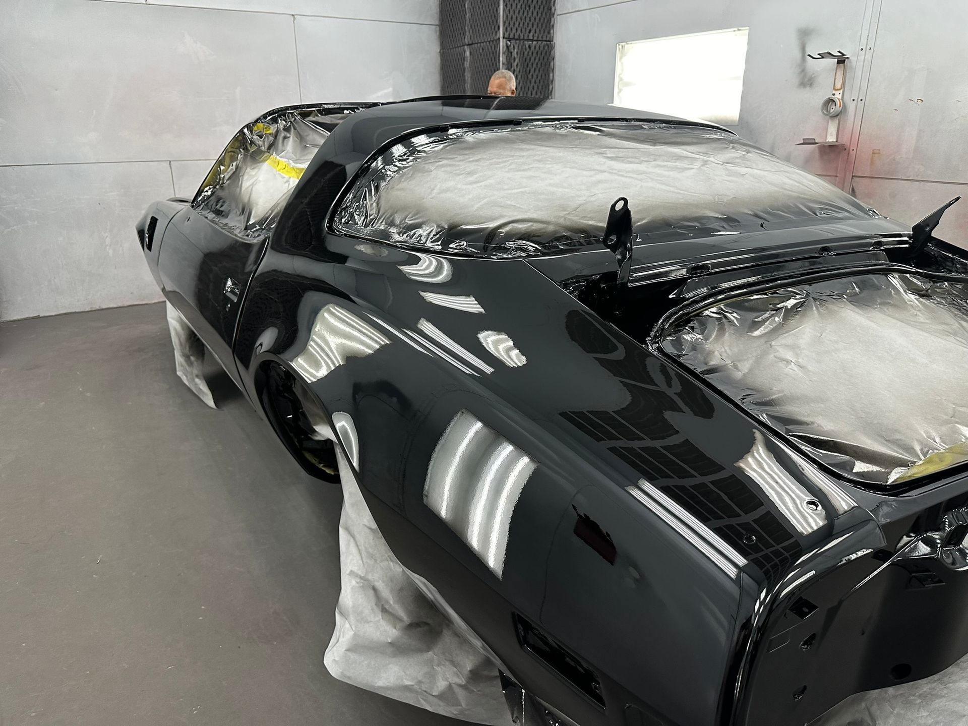 A black car is being painted in a garage.