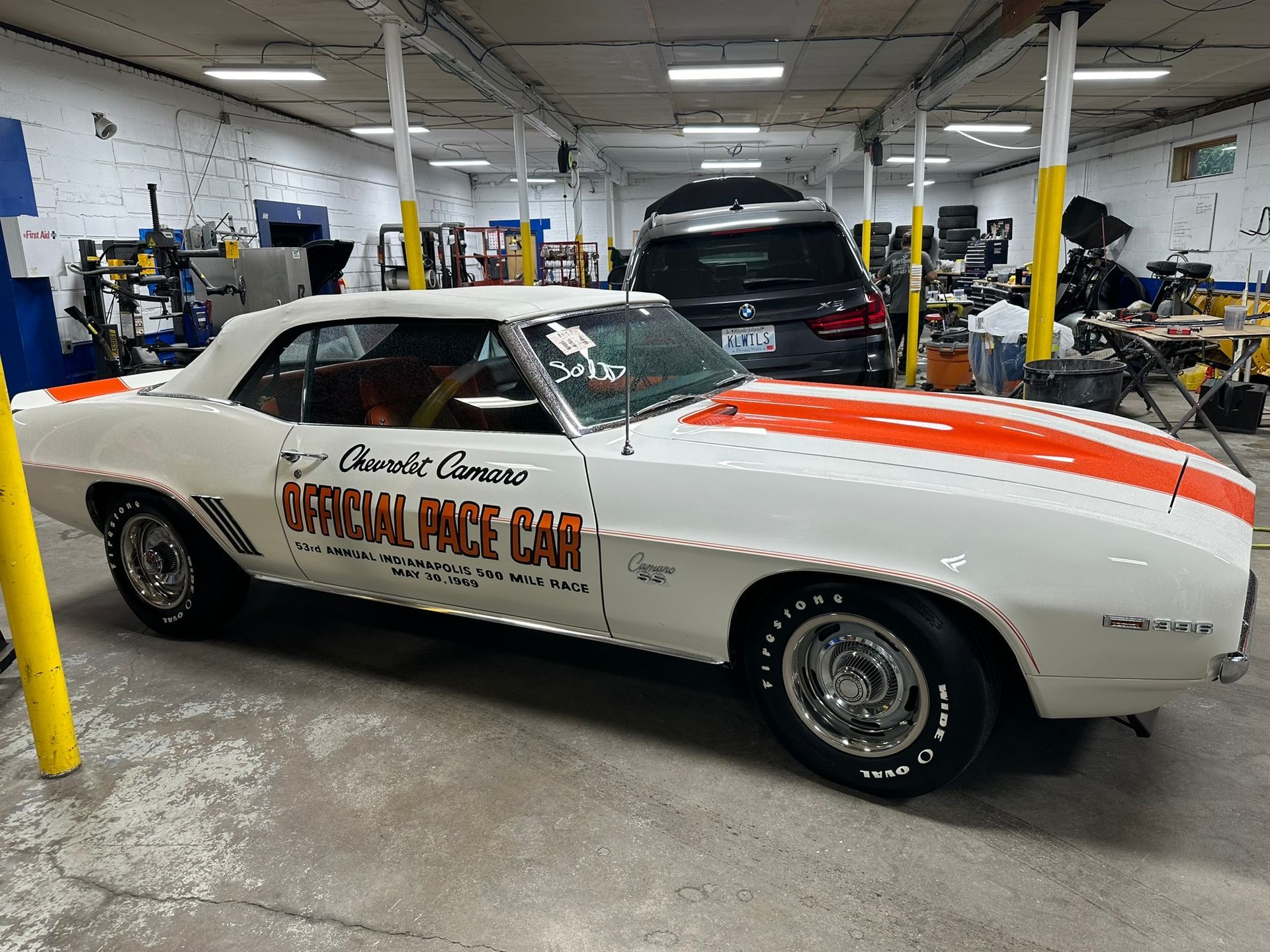A white and orange race car is parked in a garage.