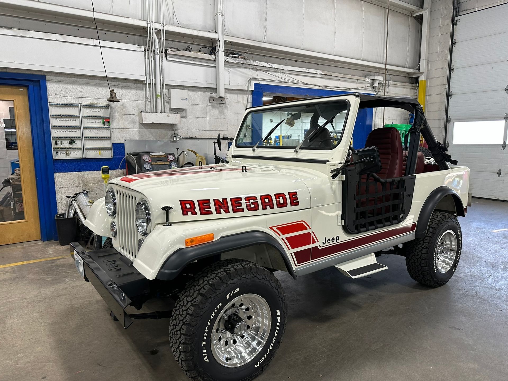 A white renegade jeep is parked in a garage.