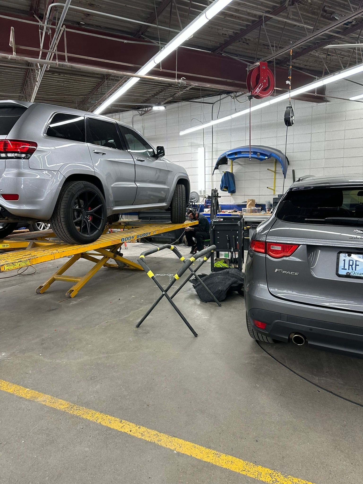 Two cars are sitting on a lift in a garage.
