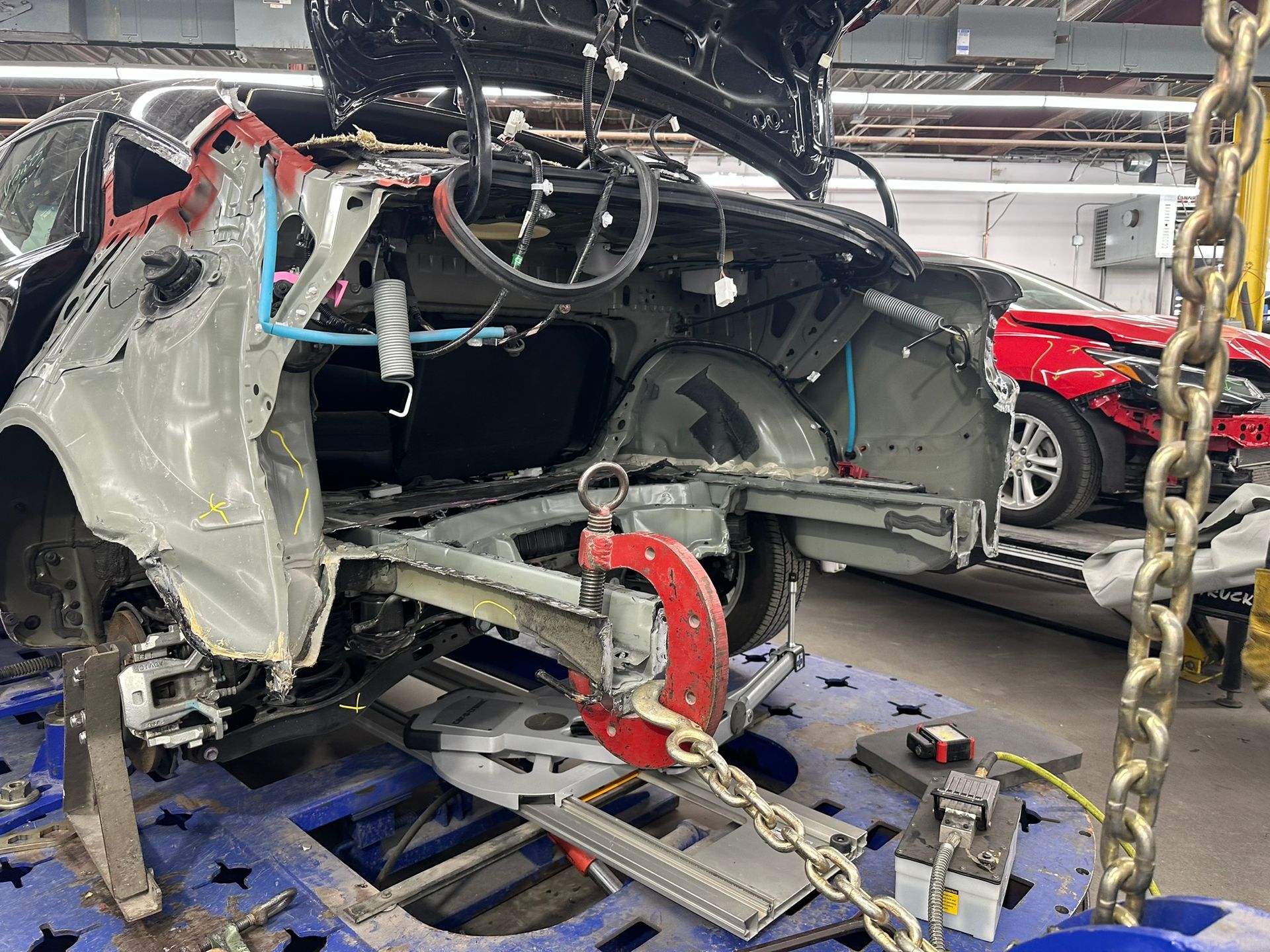 A car is being worked on in a garage with the hood up.