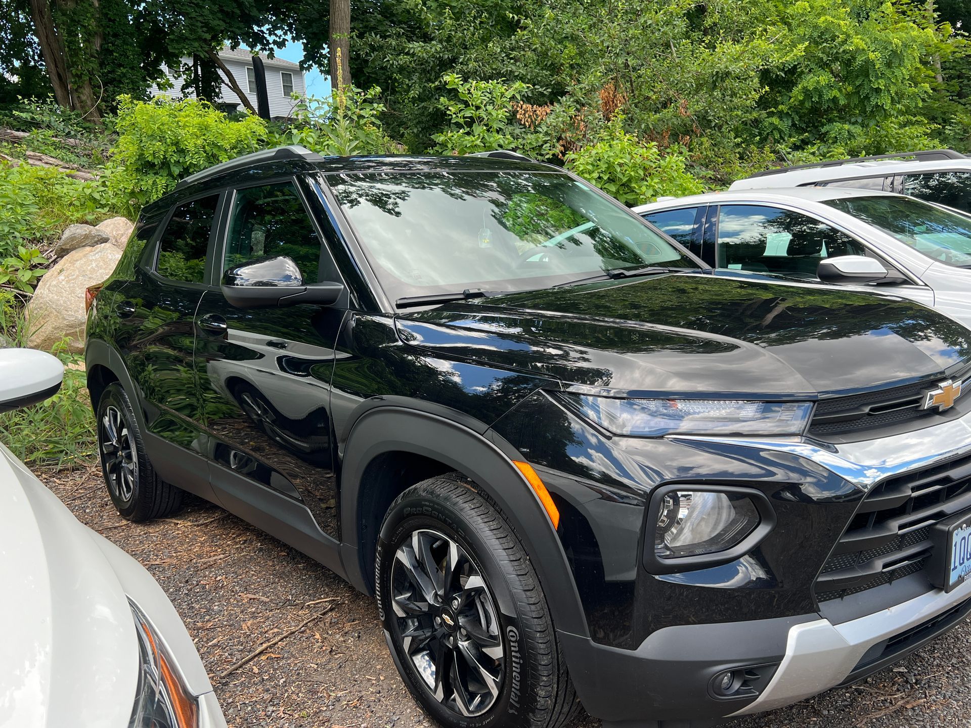 A black chevrolet trailblazer is parked next to a white car.
