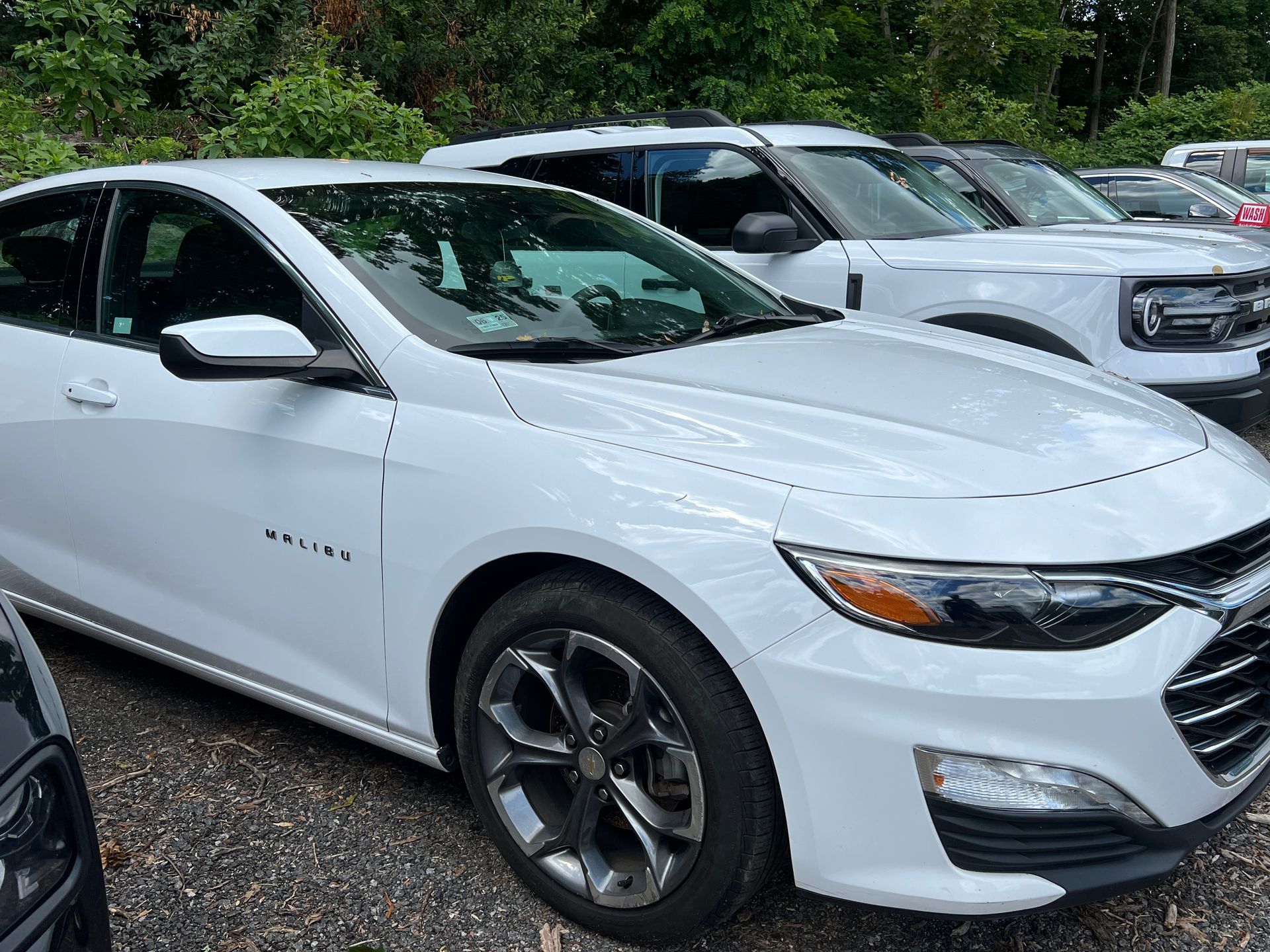 A row of white cars are parked in a parking lot.