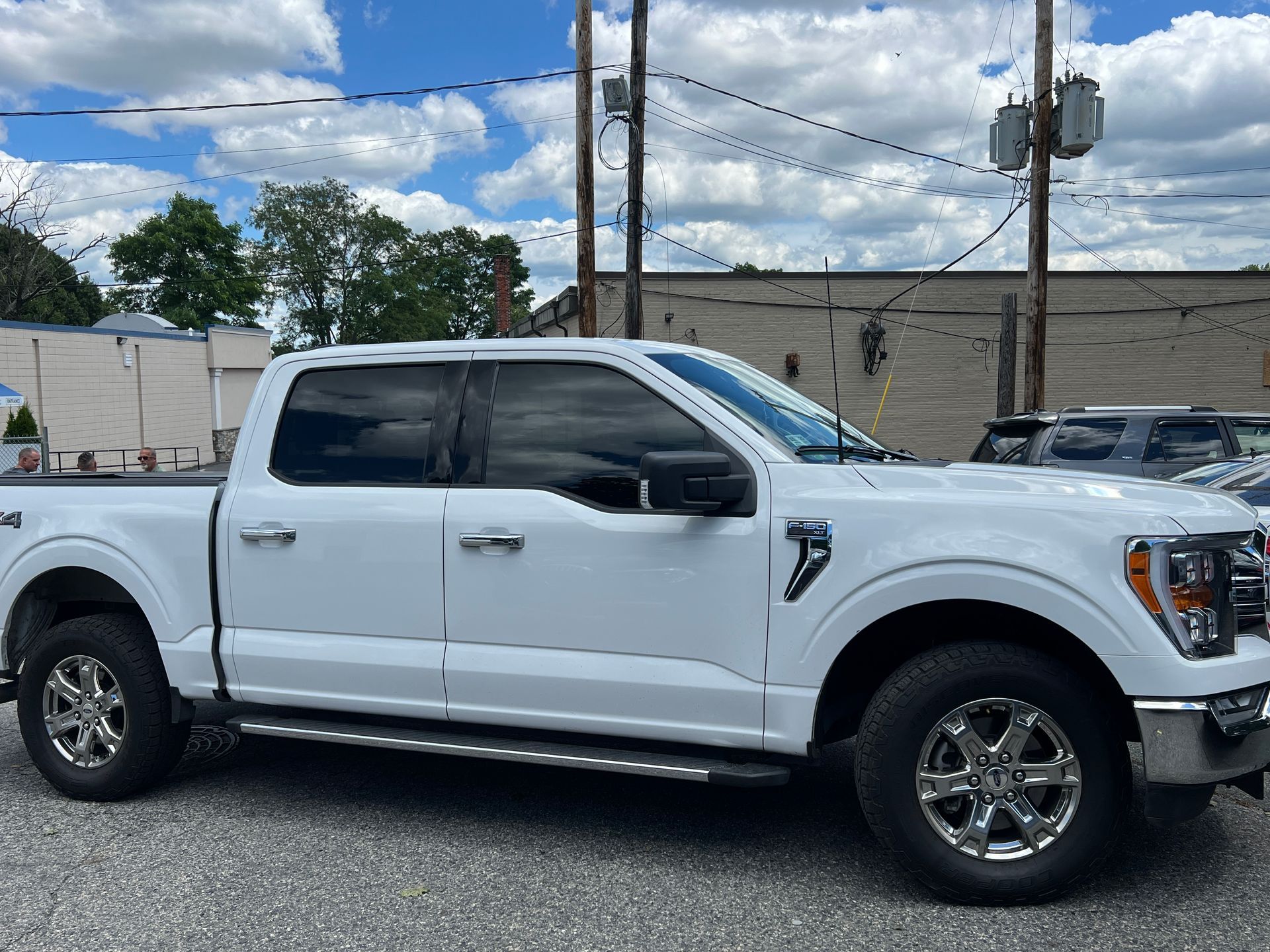 A white pickup truck is parked in a parking lot in front of a building.