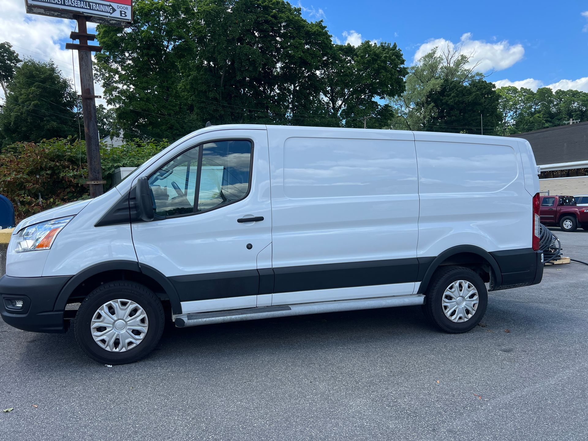 A white van is parked in a parking lot in front of a building.