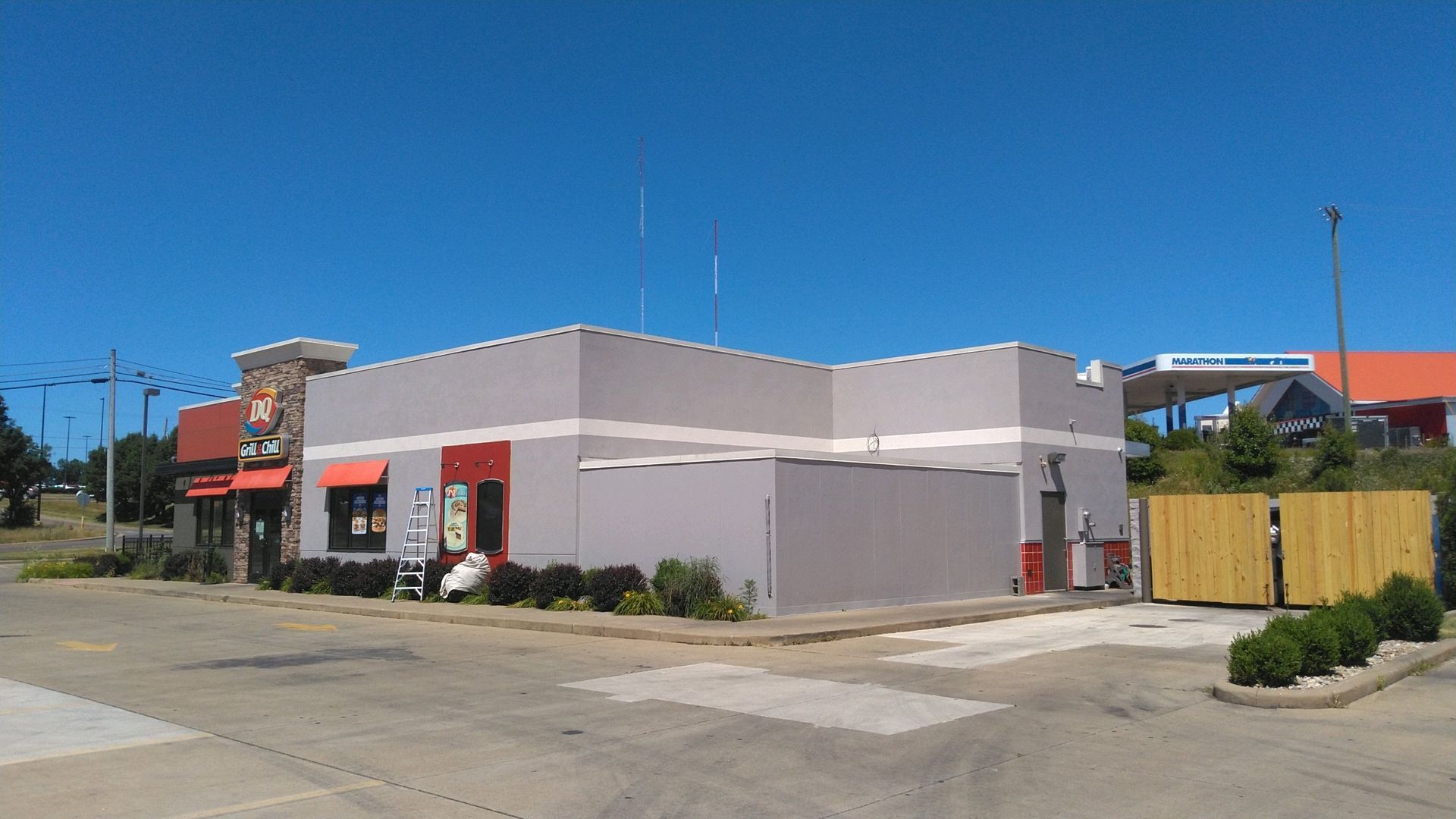 Street corner with a gray and red commercial building under a clear blue sky