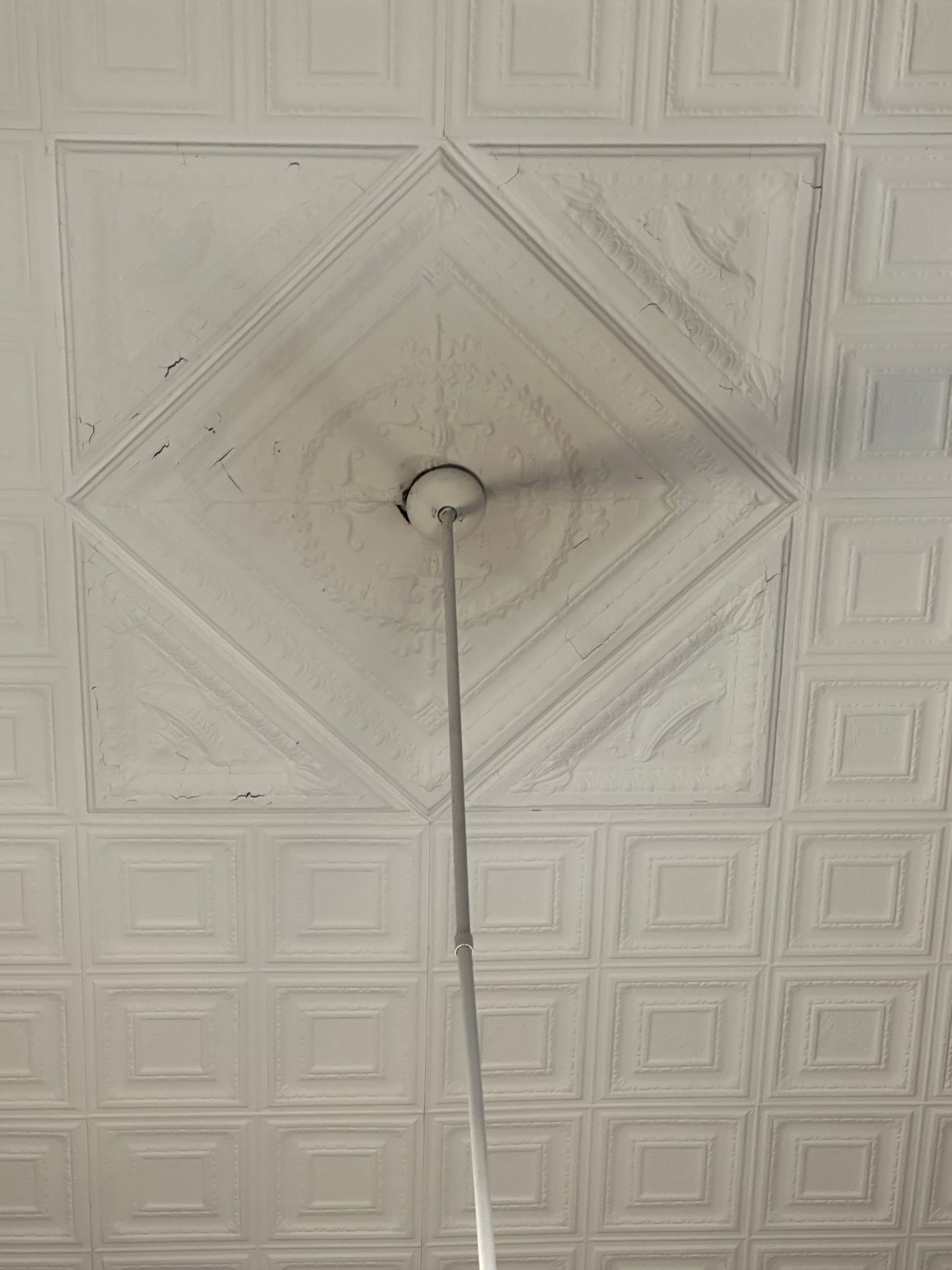 Ceiling with a hanging cord centered in a decorative white paneled pattern