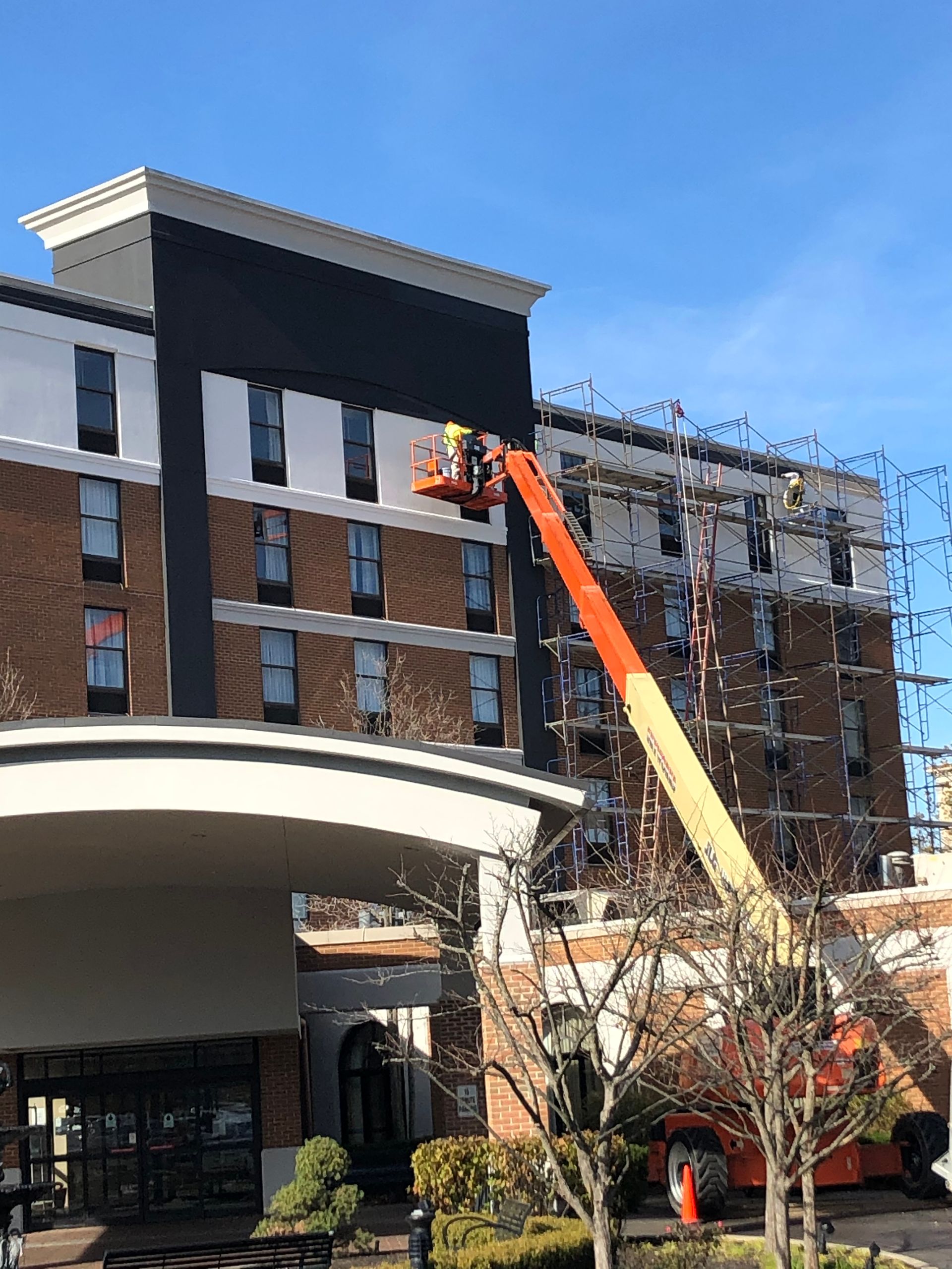 Construction crane working on a multi-story building with brick and black facade panels