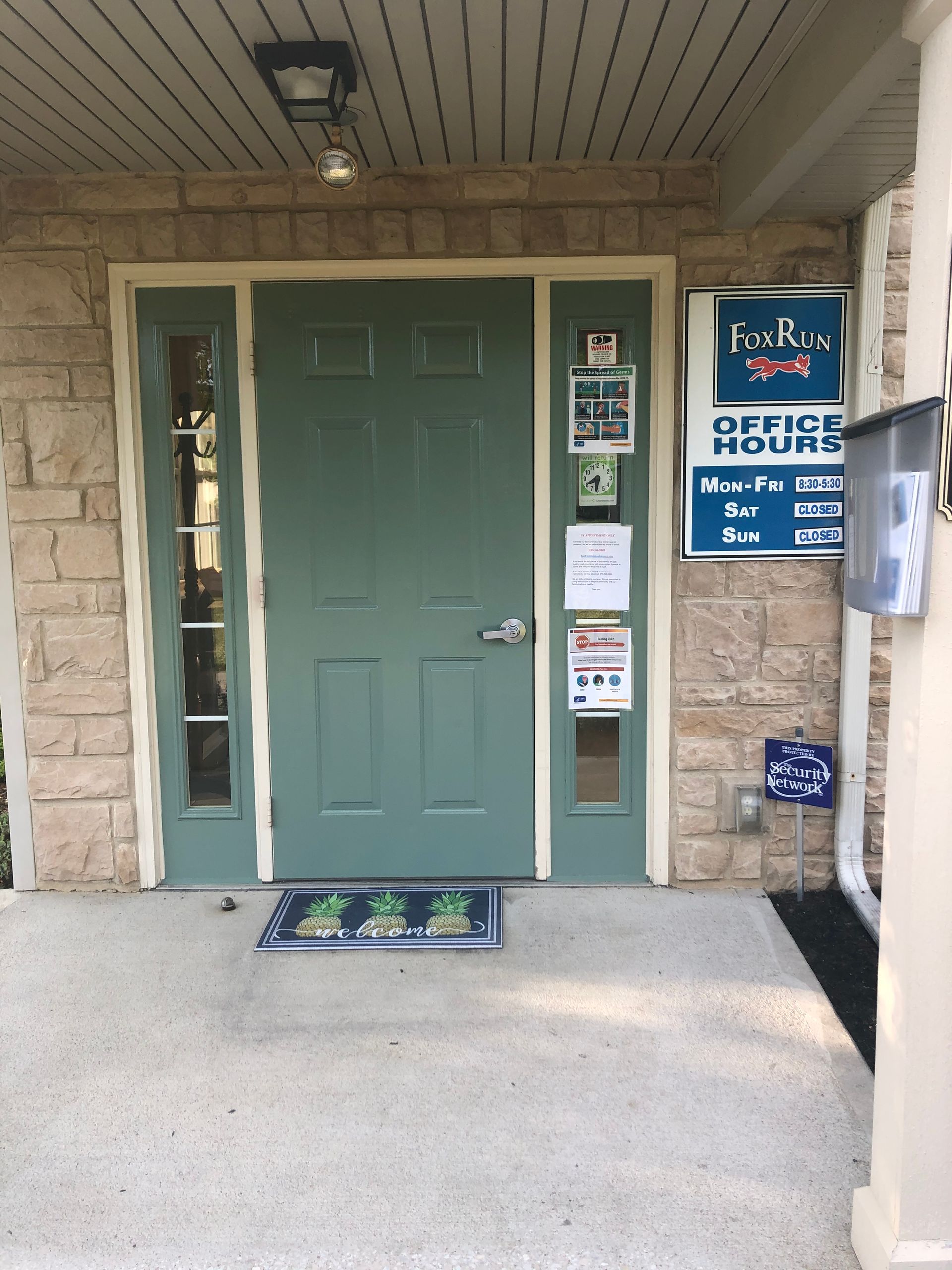 Apartment entry with green door, stone walls, and office sign beside the entrance