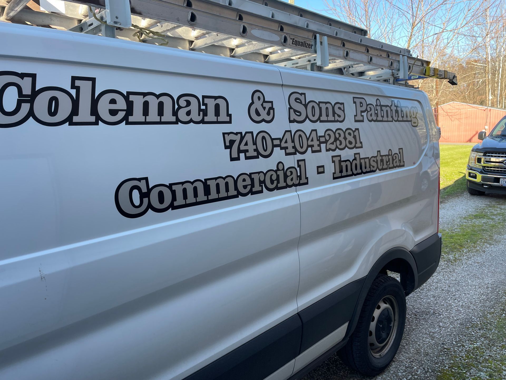 White Coleman & Sons Plumbing commercial van with company logo and phone number parked on gravel.