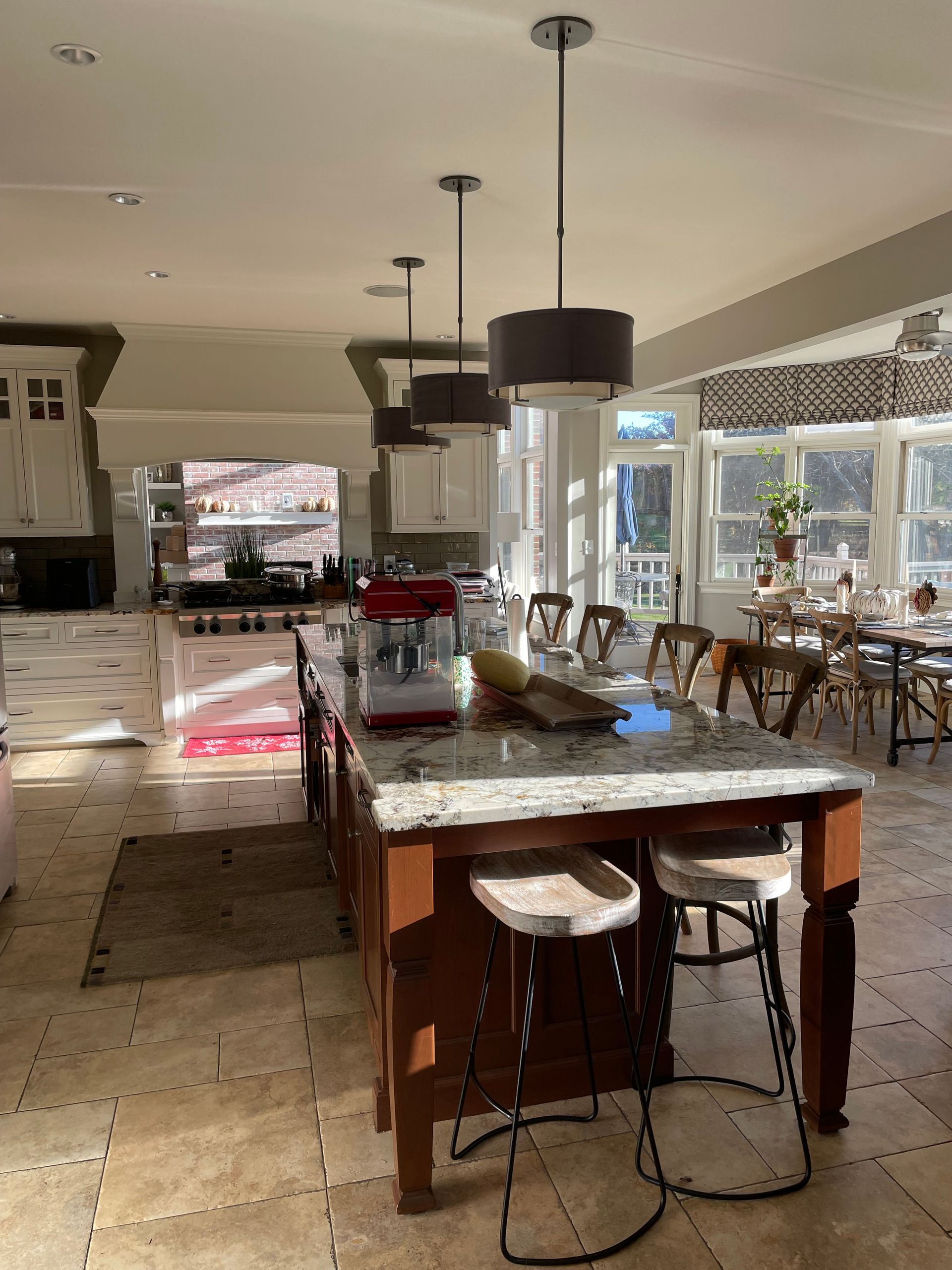 Elegant dining room with a marble table, red chairs, and large windows overlooking a bright outdoor patio