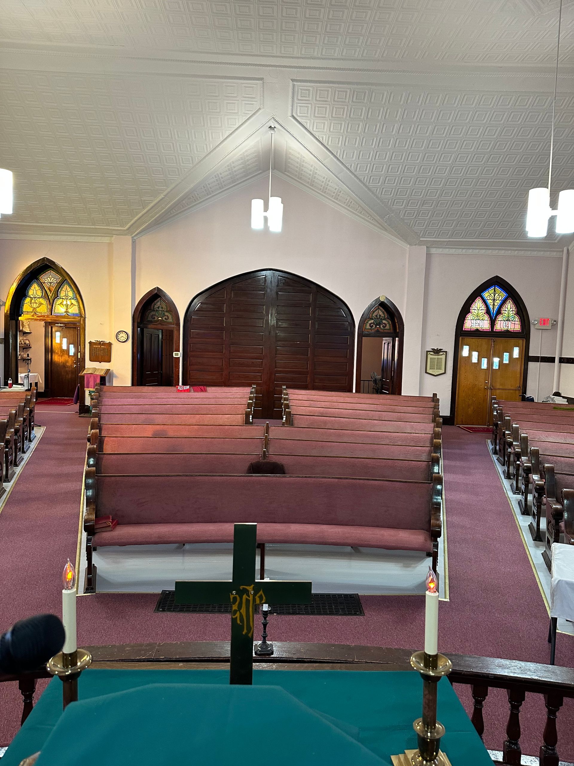 Interior of a church with pink pews, arched stained-glass windows, and a high vaulted ceiling.