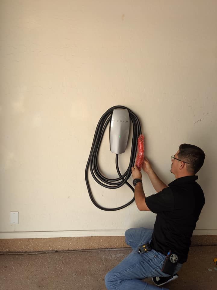 A man is installing a tesla charging station on a wall.
