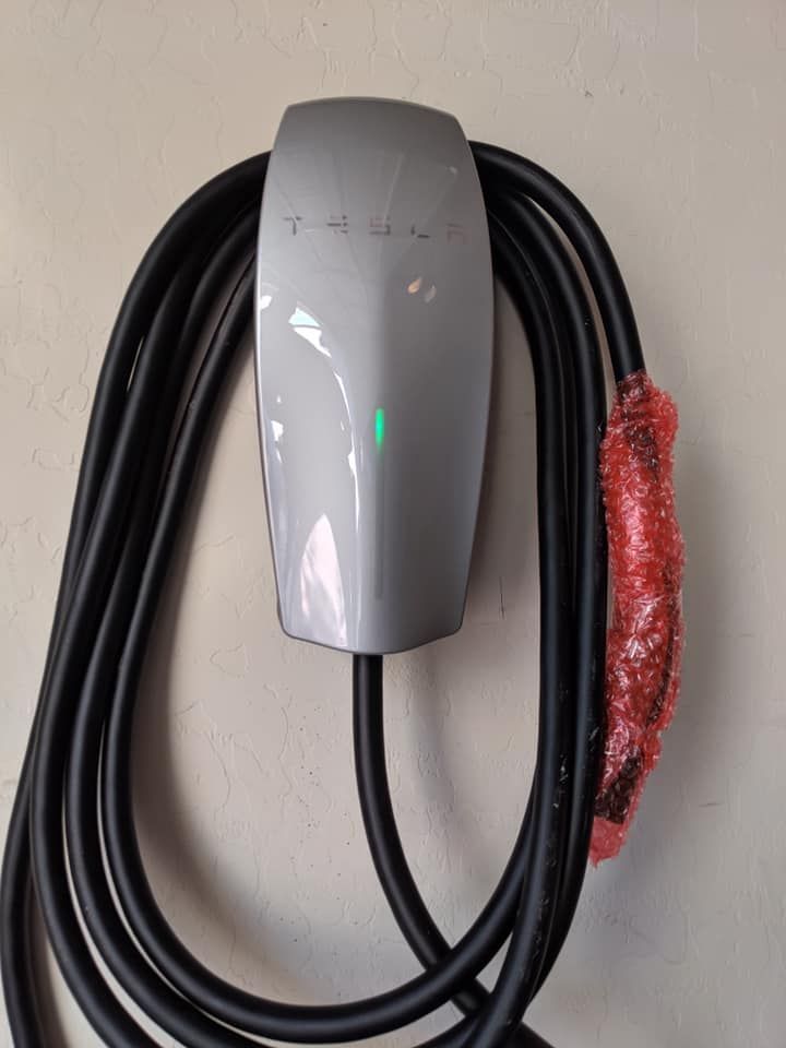 A tesla charging station with a cable attached to it.