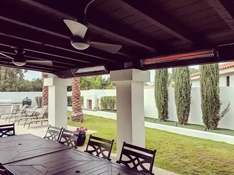A patio with a table and chairs and a ceiling fan.