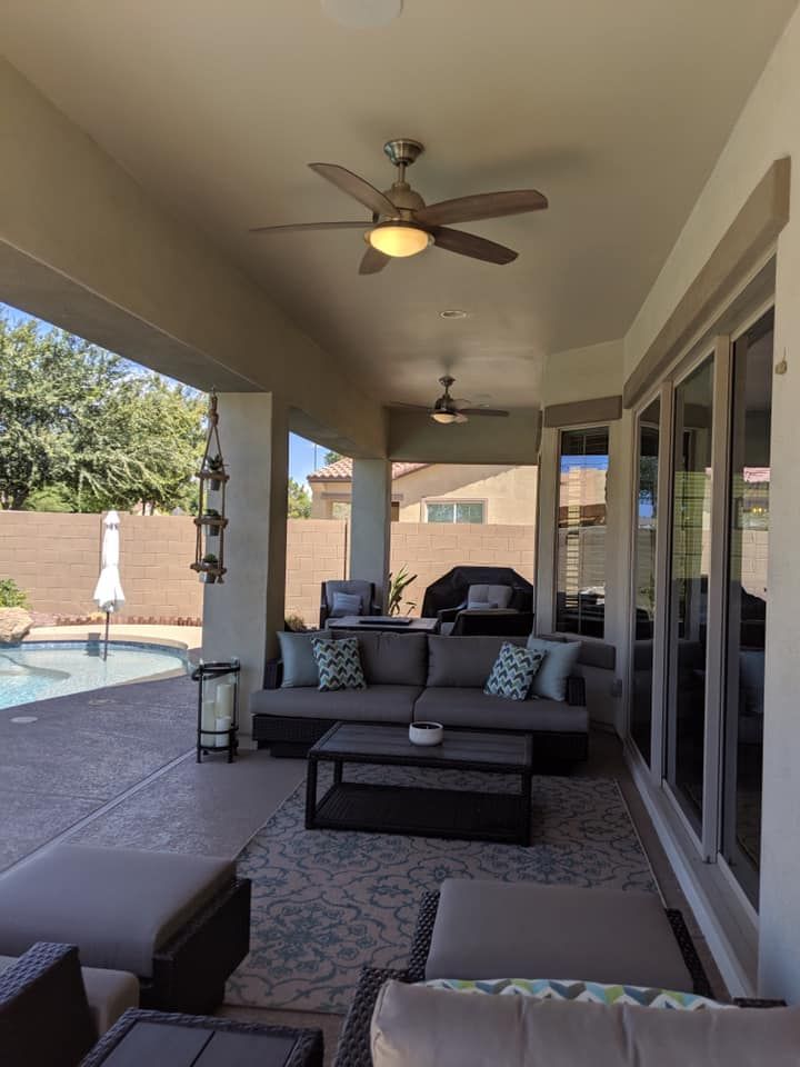 A patio with a couch , coffee table , and ceiling fan.