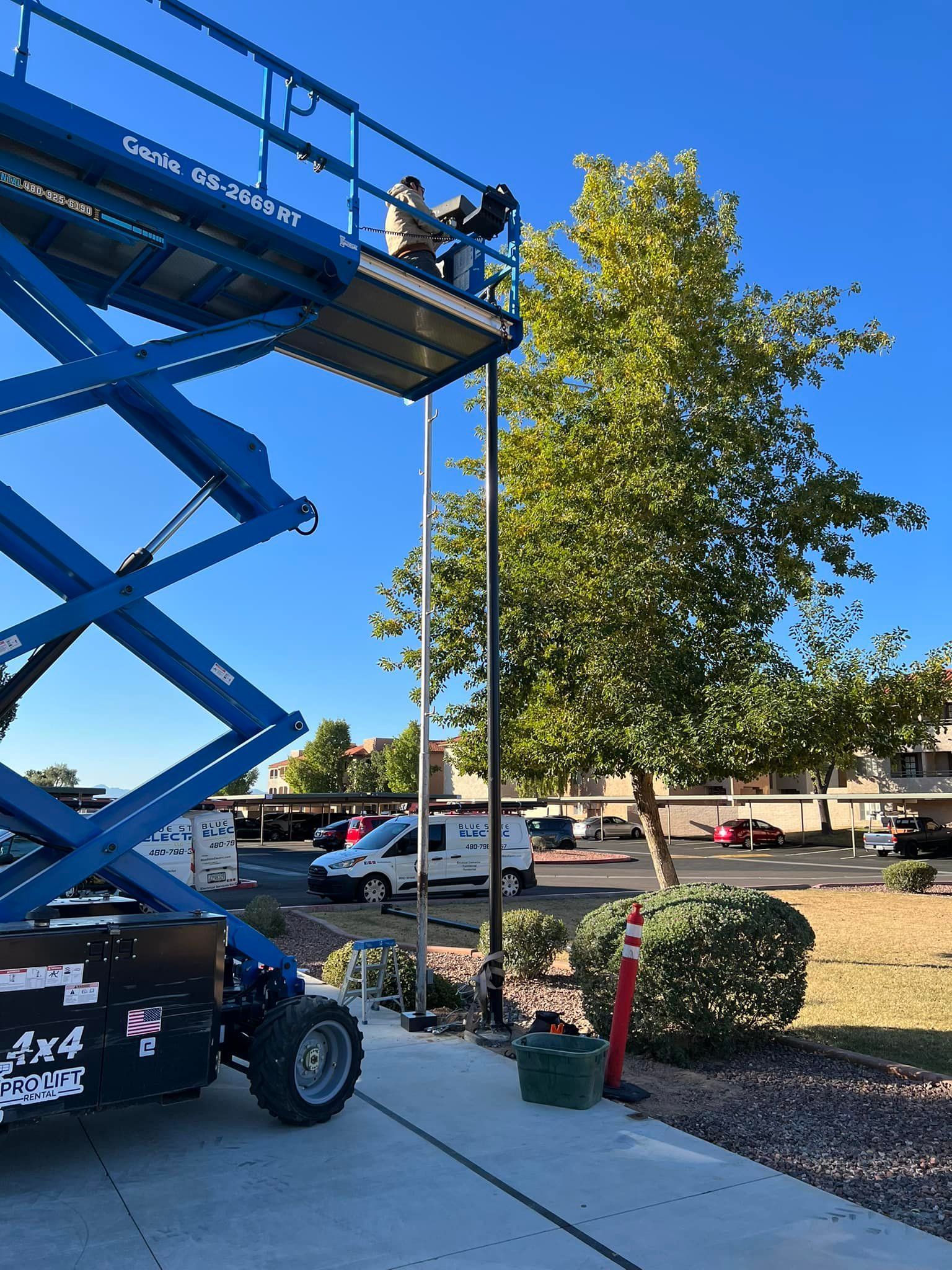 A man is standing on top of a blue scissor lift.