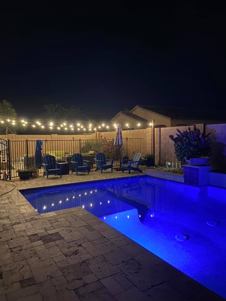 A large swimming pool is lit up at night with blue lights.