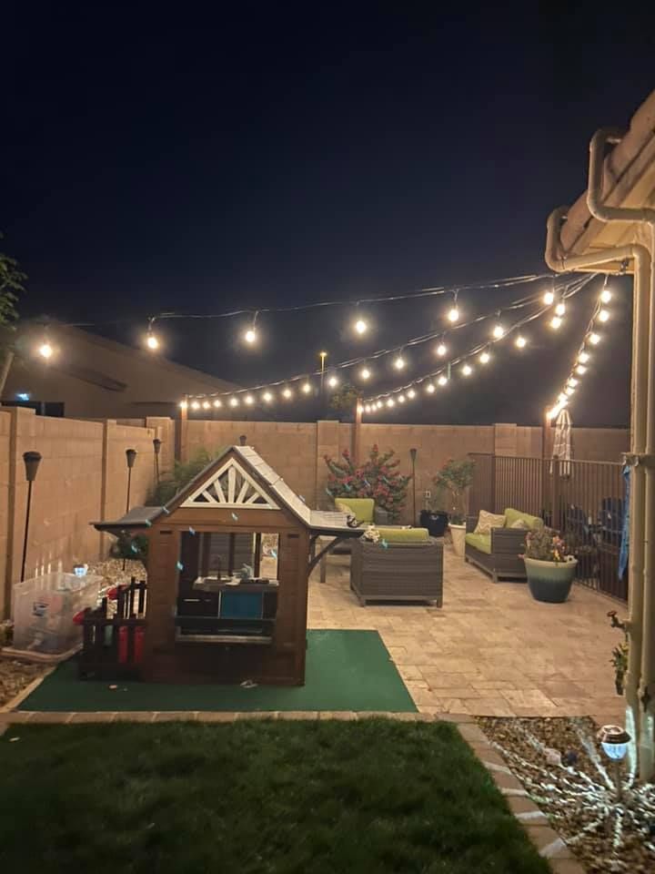 A backyard with a playhouse and string lights at night.