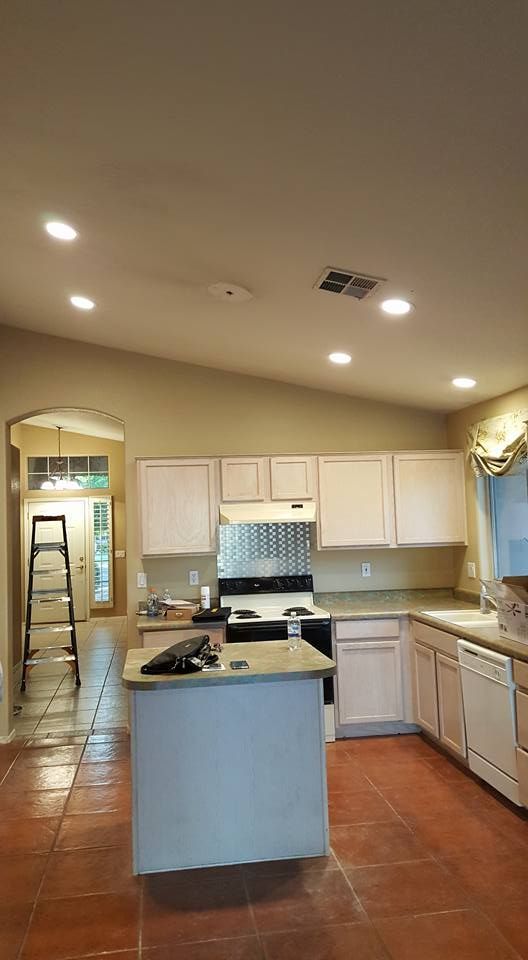 A kitchen with white cabinets , a stove , a sink , and a ladder.