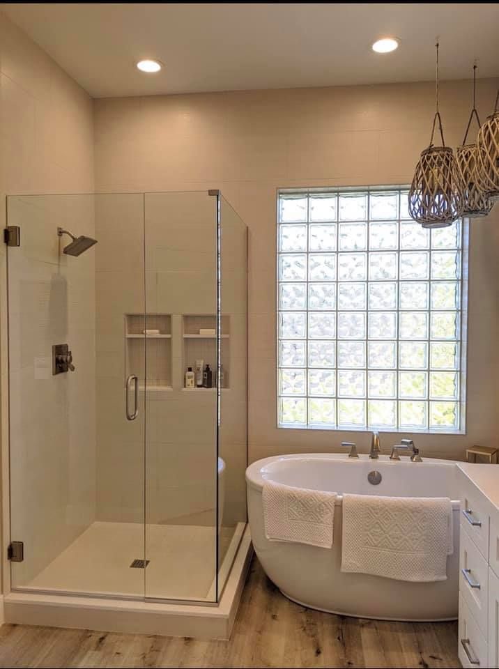 A bathroom with a tub , shower , and window.