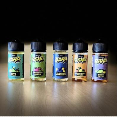 Five bottles of e liquid are lined up on a table.