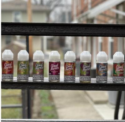 Several bottles of good morning e liquid are lined up on a shelf.