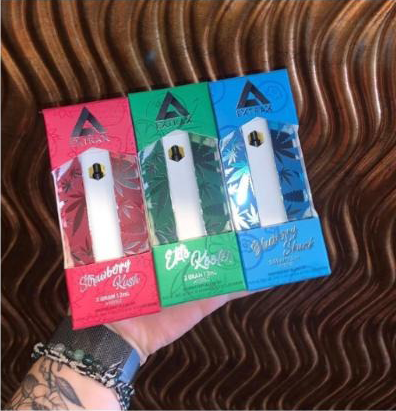 A person is holding three electronic cigarettes in their hand