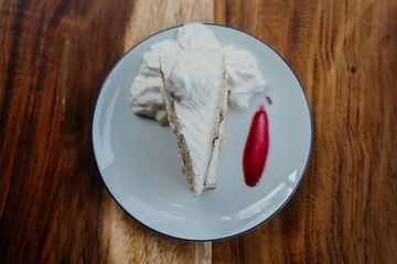 A slice of cake on a white plate on a wooden table.