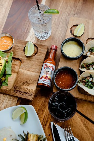 A wooden table topped with plates of food and a bottle of Tabasco sauce.