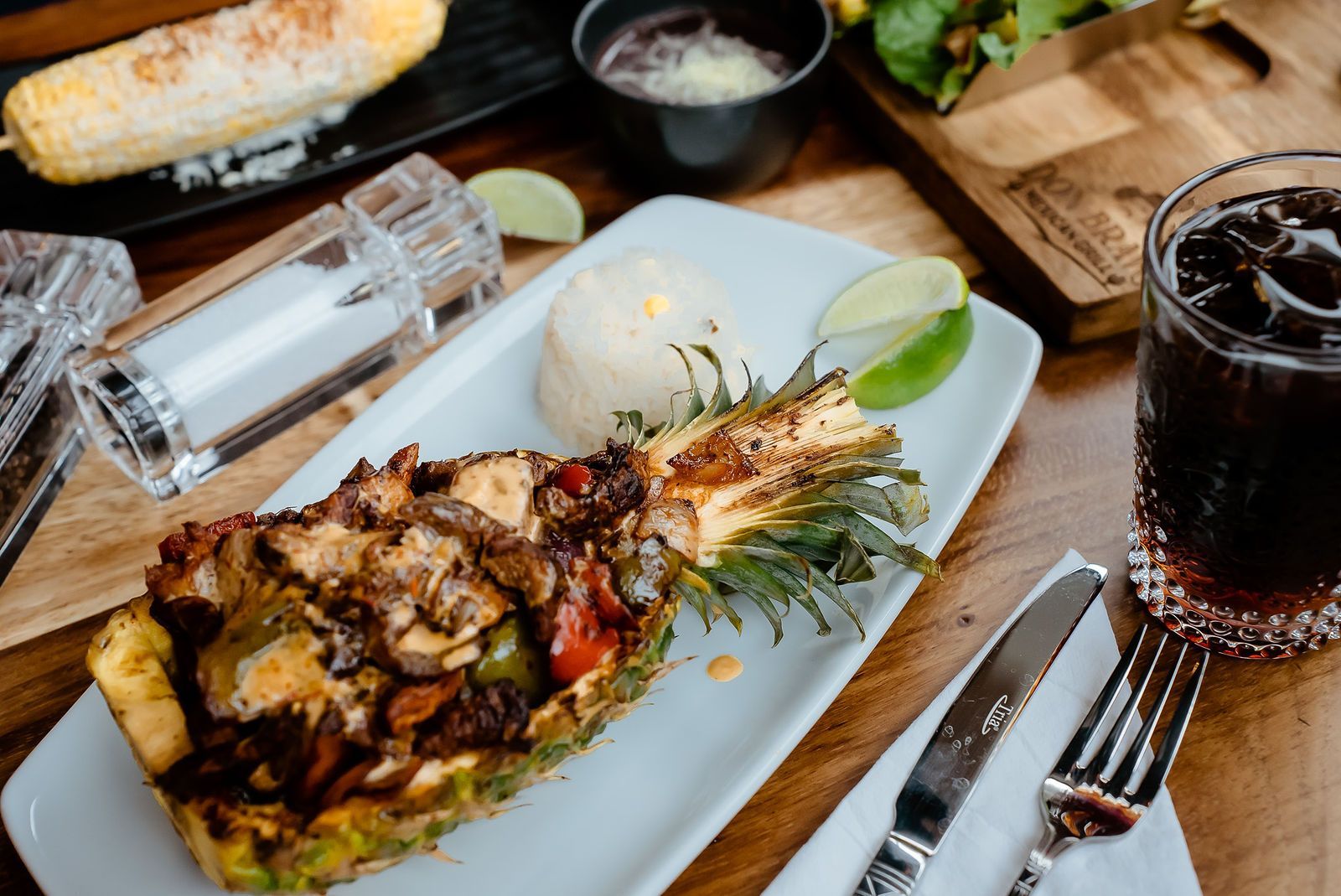 A white plate topped with a pineapple filled with meat and vegetables.